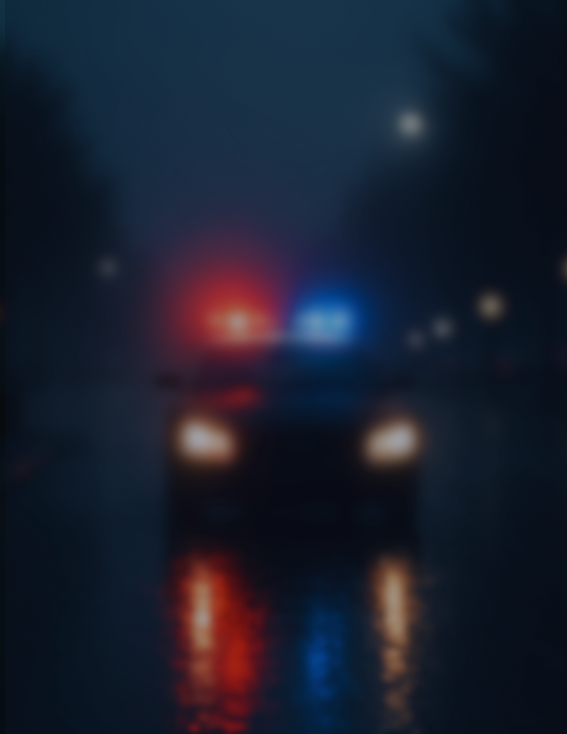 A police car stopped in the middle of a dark and rainy scene on a quiet road.
